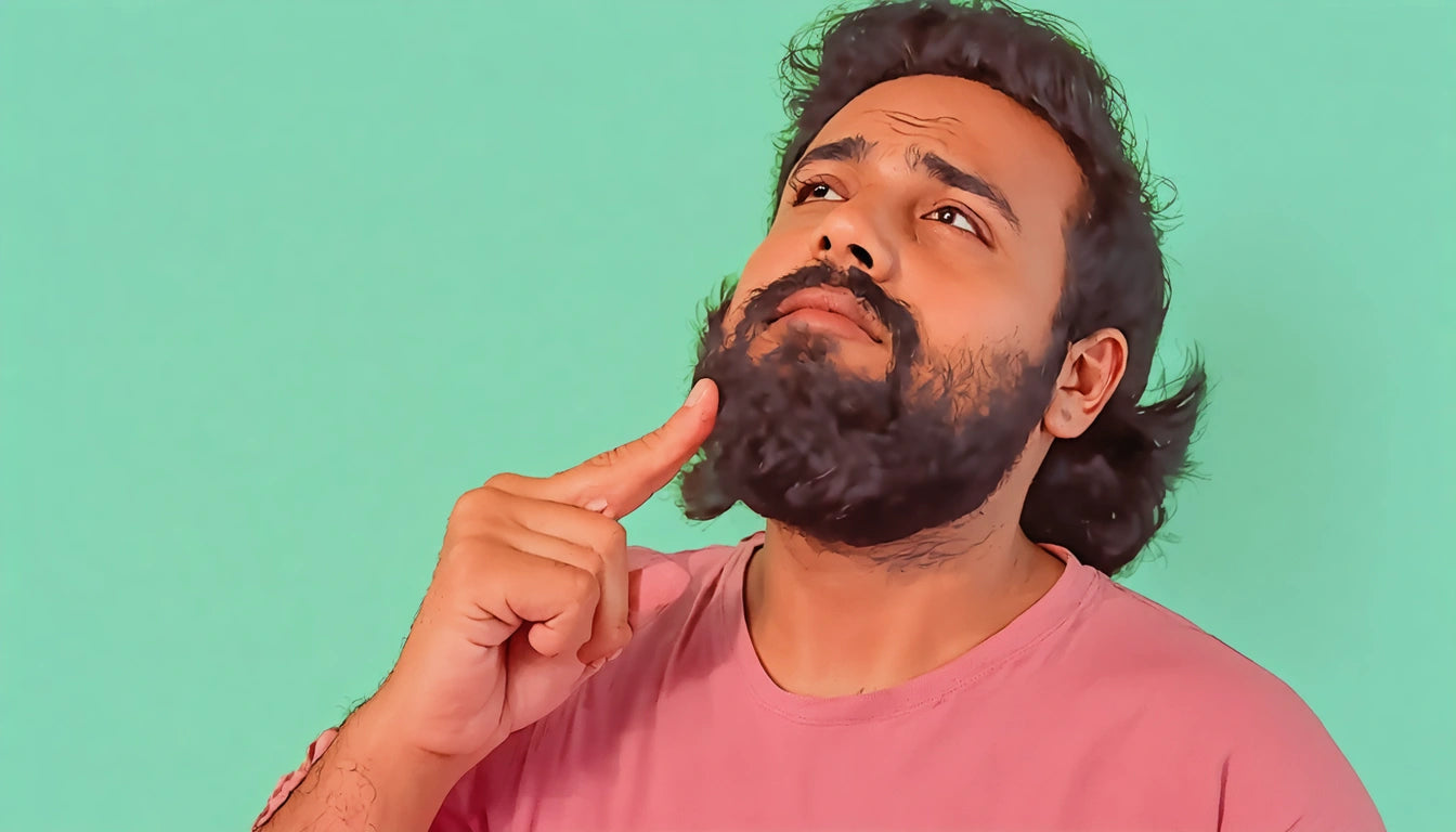 Man with beard and pink shirt touching chin, looking upward against a green background