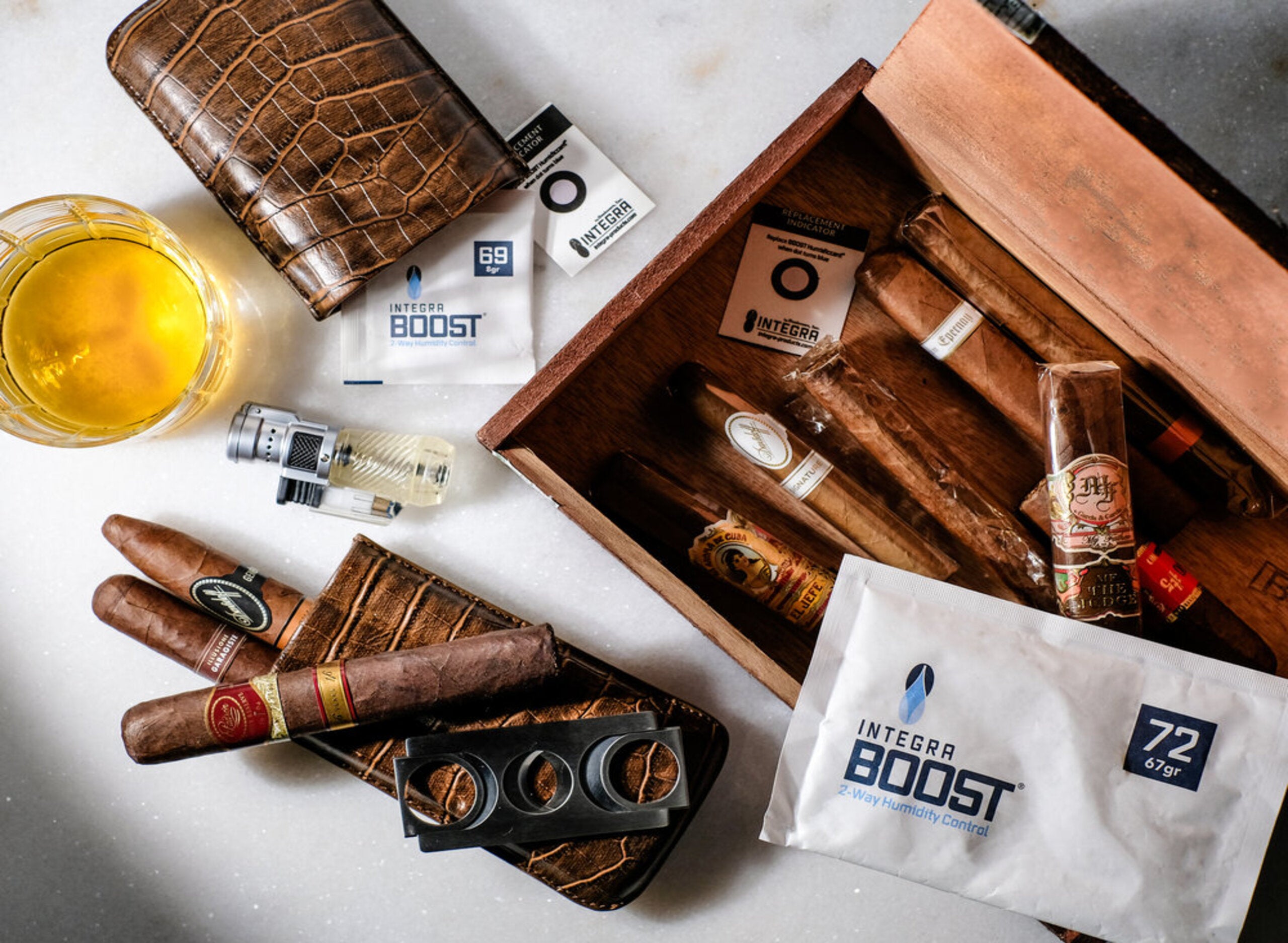 Five brown cigars with gold bands, some partially smoked, lying on a wooden surface with small pieces of tobacco scattered